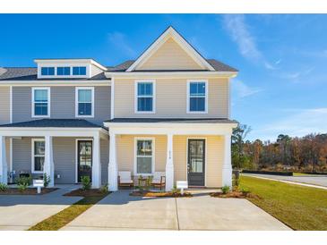 Charming townhome showcasing a well-maintained front yard, covered entry, and a modern architectural design under a clear blue sky at 827 Alma Square Dr, Moncks Corner, SC 29461