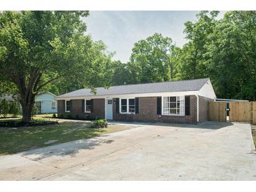 Charming brick ranch-style home with a well-manicured lawn, mature trees, and a long driveway at 3227 Stonehaven Dr, North Charleston, SC 29420