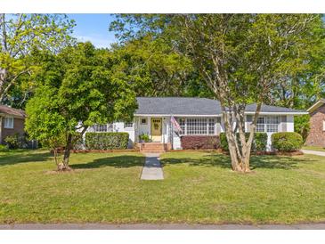 Charming home with a well-manicured lawn, mature trees, and a welcoming yellow front door at 405 Cross St, Charleston, SC 29407