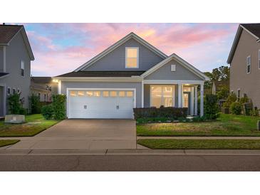 Charming single-Gathering home with a well-manicured lawn and a two-car garage at dusk at 411 Freeland Way, Moncks Corner, SC 29461