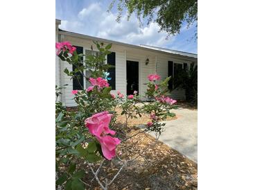 Charming home featuring blooming roses in the front yard, enhancing curb appeal and a welcoming ambiance at 1220 Apex Ln, Charleston, SC 29412