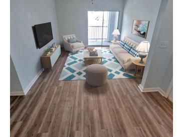 Bright living room featuring wood floors, a modern sofa, area rug, and view to an outdoor balcony at 1300 Park West Blvd # 406, Mount Pleasant, SC 29466