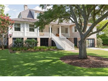 Charming two-story home with landscaped yard, large tree, and elevated front porch at 2407 Atlantic Ave, Sullivans Island, SC 29482