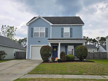 Charming two-story home with light-blue siding, a well-manicured lawn, and a driveway leading to an attached garage at 328 Bradley Bend Dr, Moncks Corner, SC 29461