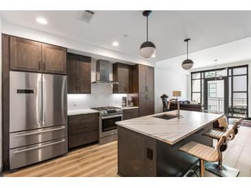 Modern kitchen with stainless steel appliances, marble countertops, island with bar stools, and dark brown cabinetry at 5 Gadsdenboro St # 416, Charleston, SC 29401
