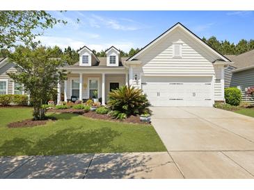 Charming white home features manicured lawn, beautiful landscaping, and attached two-car garage at 559 Eastern Isle Ave, Summerville, SC 29486