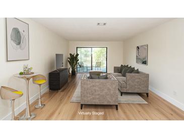 Bright, staged living room features wood floors, bar area, and access to the outside at 8483 Yadkin Cir # C, North Charleston, SC 29418