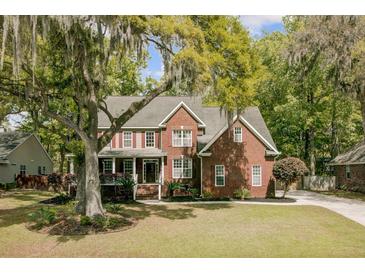Charming two-story brick home featuring a well-manicured lawn, mature trees, and welcoming front porch at 8781 Laurel Grove Ln, North Charleston, SC 29420