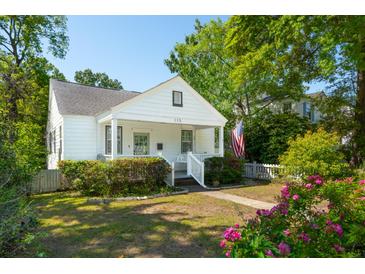 Charming white home featuring a well-manicured lawn, a quaint front porch, and the American flag at 115 Peachtree St, Charleston, SC 29403
