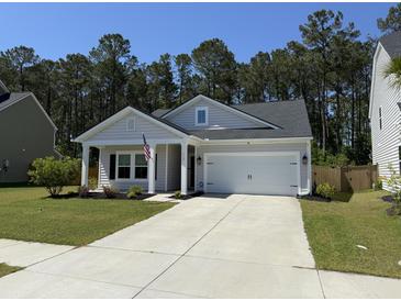 Charming single-story home featuring a two-car garage, manicured lawn, and inviting front porch at 117 Camellia Bloom Dr, Moncks Corner, SC 29461