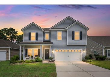 Charming two-story home with gray siding, black shutters and a well-manicured lawn at sunset at 3438 Great Egret Dr, Johns Island, SC 29455