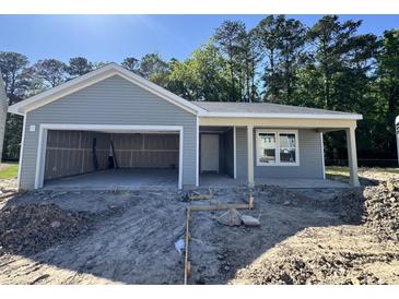 Charming single-story home with light gray siding and an attached garage, set against a backdrop of trees at 5031 Scow Ct, Summerville, SC 29485
