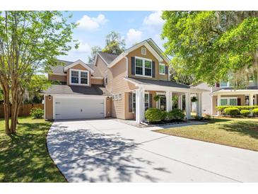 Inviting two-story home featuring a spacious front porch and a well-manicured lawn with mature trees at 5471 Rising Tide, North Charleston, SC 29420