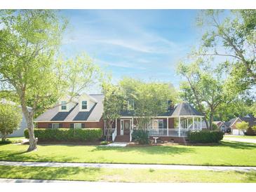 Charming brick home featuring a manicured lawn, mature trees, and a welcoming front porch with gazebo at 100 N Gateshead Xing, Goose Creek, SC 29445