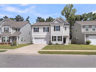 Charming two-story home with a manicured lawn, attached garage and inviting front porch with dark door at 1167 Mossy Rock Dr, Summerville, SC 29485