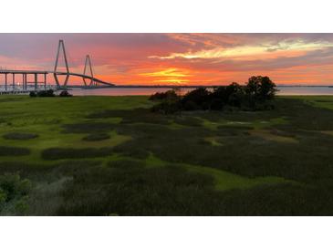 Scenic marsh view with a vibrant sunset and bridge in the distance, showcasing the natural beauty of the location at 136 Cooper River Dr, Mount Pleasant, SC 29464