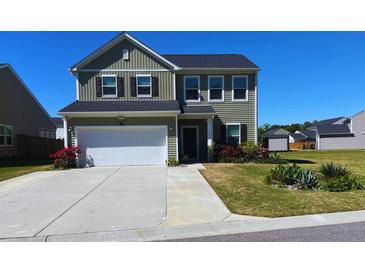 Charming two-story home featuring a two-car garage, manicured lawn, and vibrant flower beds adding curb appeal at 167 Cypress Plantation Rd, Moncks Corner, SC 29461
