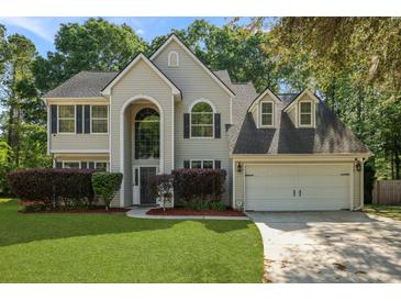 Two story home featuring a manicured front yard, two-car garage and mature trees at 5418 Percival Ln, Charleston, SC 29420