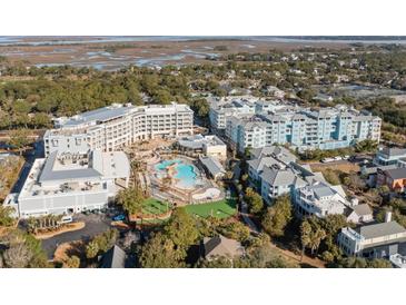 Aerial view of a luxurious resort with pools, lush landscaping, and stunning coastal views at 5802 Palmetto Dr # B-501, Isle of Palms, SC 29451
