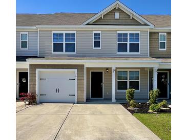 Charming townhome with attached garage and covered entryway, complemented by a well-maintained lawn and blue skies at 703 Hilchot Dr, Summerville, SC 29486