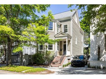 Charming two-story home with landscaped yard, porch, and black car in the driveway at 76 Radcliffe St, Charleston, SC 29403