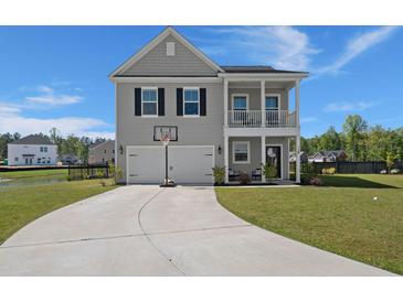 Charming two-story home with a front porch, two-car garage, basketball hoop, and a well-manicured lawn at 118 Jesup Ct, Ridgeville, SC 29472