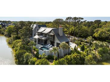 Stunning multilevel home featuring a private pool, balcony, and serene water views surrounded by lush greenery at 20 Old Cedar Ln, Kiawah Island, SC 29455