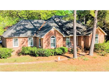 Charming brick home featuring a well-manicured lawn and mature trees providing ample shade at 301 Factors Walk, Summerville, SC 29485