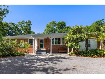 Charming brick home featuring a landscaped yard, gravel driveway, and covered front porch at 5907 Murray Dr, Hanahan, SC 29410