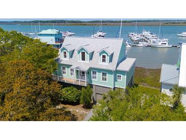 Charming waterfront home boasts delightful curb appeal with its coastal color scheme, dormer windows, and lush landscaping at 68 W 9Th St # B, Folly Beach, SC 29439