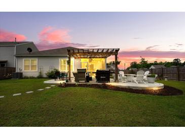Outdoor patio area with pergola, grill, dining table and sunset ambiance make this space great for entertaining at 9781 Roseberry St, Ladson, SC 29456