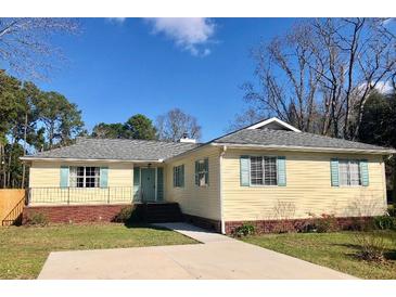Charming ranch-style home featuring a well-manicured lawn, light yellow siding, and inviting blue shutters at 1120 Seaside Ln, Charleston, SC 29412