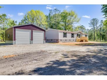 Charming single-story home with an oversized two car detached garage and a large unpaved driveway at 254 Nelson Farm Ln, Cross, SC 29436