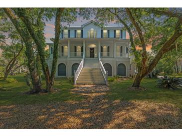 Stately two-story home with white trim, porch, and grand staircase, framed by beautiful mature trees at 4386 Park Island Rd, Hollywood, SC 29449