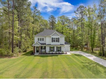 Charming two-story home with manicured lawn, attached garage, and inviting front porch at 5005 Buckland Trl, Ridgeville, SC 29472
