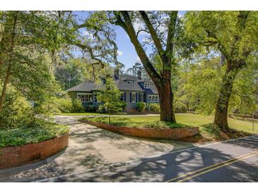 Charming home with mature trees, brick accents, and a circular driveway, offering curb appeal and natural beauty at 503 W Carolina Ave, Summerville, SC 29483