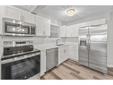 Bright kitchen features stainless steel appliances, white cabinets, quartz countertops, and stylish lighting at 415 Parkdale Dr # 2B, Charleston, SC 29414