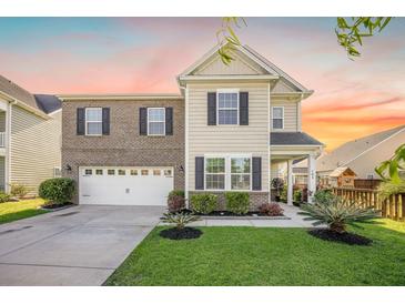 Charming two-story home boasts a mix of brick and siding, well-manicured lawn and attached two-car garage at 103 Radtko Rd, Summerville, SC 29486