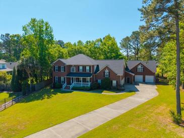 Beautiful brick two-story home with a well-manicured lawn, long driveway, and an attached three-car garage at 105 Birkbeck Ct, Goose Creek, SC 29445