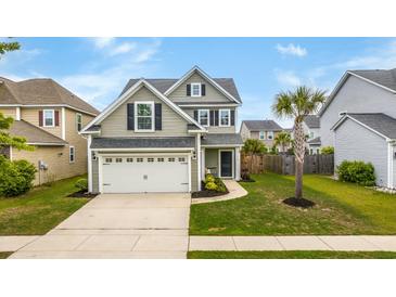 Charming two-story home features a well-manicured lawn and attached two-car garage with neutral siding and a palm tree at 1426 Tannery Row, Johns Island, SC 29455
