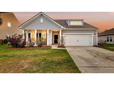 Charming single-Gathering home with a well-manicured lawn, attached garage, and inviting front porch at 3431 Great Egret Dr, Johns Island, SC 29455