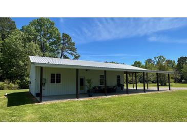 Spacious single-story home with covered porch and ample green lawn and mature tree coverage at 4911 Chisolm Rd, Johns Island, SC 29455