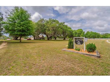 Expansive front yard with mature trees and Rockin H Farm sign in front of home with white picket fence at 7875 Berry Manor Ln, Edisto Island, SC 29438