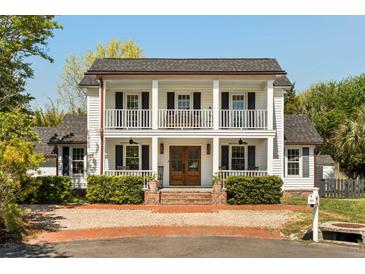 Charming two-story home showcasing a double porch, manicured landscaping, and a welcoming brick driveway at 930 Richter Way, Mount Pleasant, SC 29464