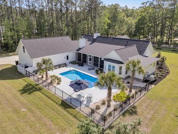 An aerial view of a stunning home showcasing a beautiful pool surrounded by lush landscaping and a black aluminum fence at 1245 Saddlehorn Rd, Summerville, SC 29486
