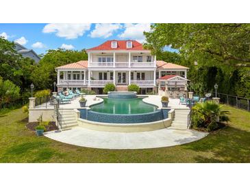 An extravagant two-story home boasts a stunning backyard pool with lounge chairs and a bar area for outdoor entertaining at 13 Broughton Rd, Charleston, SC 29407