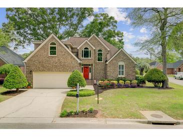 Charming brick home featuring a manicured lawn, colorful flowerbeds, and an inviting red front door at 1391 Southlake Dr, Mount Pleasant, SC 29464