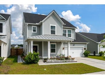 Charming two-story home with a well-manicured lawn, metal roof, and a welcoming front porch at 206 Evergreen Ave, Summerville, SC 29485