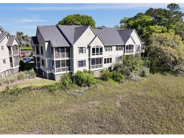 Condo building with a dark gray roof with screened in porches on each floor overlooking grassy waterfront at 2134 Landfall Way, Seabrook Island, SC 29455