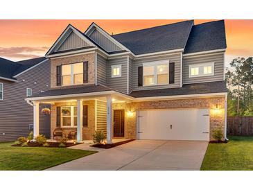 Inviting two-story home showcasing a brick and gray facade, well-manicured lawn, and a charming front porch at 214 Squire Pope Rd, Summerville, SC 29486